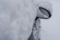 Car side mirror and car window covered with white snow across snowy city street close-up. Winter weather. Transportation. Snowstor Royalty Free Stock Photo