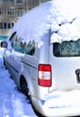 car in the snow against the background of the house on a sunny day, a large snowdrift of snow, reflections in the glass Royalty Free Stock Photo