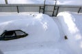 Car in a snowdrift near the house, top view. The passenger car was covered with snow. There is a lot of snow outside