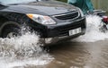 Car splashes through a large puddle on a flooded street