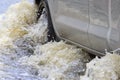 Car splashes through a large puddle on a flooded