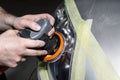 A car sprayer polishes the headlamp with a pneumatic sponge grinder.