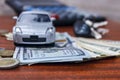 Car standing on banknotes, and next to a penny and car keys Royalty Free Stock Photo