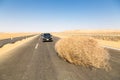 A car stopped by a giant tumbleweed on a highway with sandy dunes, between Bahariya oasis and Farafra, Western Desert of Egypt. Royalty Free Stock Photo