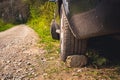 Car supported against shifting by rock in steep hill.