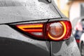Car with switched on tail light in drops of water outdoors, closeup
