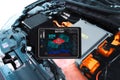 Car technician is checking SOH state of health of battery with a wireless scanner tools for electric car