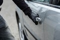 Car thief hand pulling the handle of a car