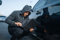 Car thief with laptop hacking alarm system Royalty Free Stock Photo