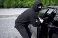 Car thief steal car breaking door criminal job burglar Hijacks Auto thief black balaclava hoodie trying break into vehicle