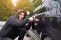 Car thief steal car breaking door criminal job burglar Hijacks  Auto thief black balaclava hoodie trying  break into vehicle Royalty Free Stock Photo