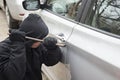 Car thief trying to break into a car with a screwdriver. Thief trying to pick the lock of a parked car Royalty Free Stock Photo