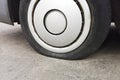 Car tire leak because of nail pounding. Flat tyre on road. Flatten punctured auto wheel. Damaged flat tire of a car on the road Royalty Free Stock Photo