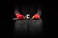 Car tire service and hands of mechanic holding new tyre on black background with copy space for text