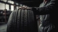 car tire shop and service - mechanic holding new tyre on garage background copy space