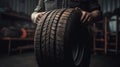 car tire shop and service - mechanic holding new tyre on garage background copy space