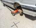 The car is at the tire shop. Under the jack the car in car-care center. The car with the removed wheel.