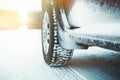 Car tires covered with snow on winter road through forest. Royalty Free Stock Photo