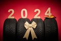 Car tires, new tyres, winter wheels gold bow ribbon present, text 2024 happy new year christmas background Royalty Free Stock Photo