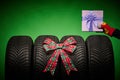 Car tires, new tyres, winter wheels, hand of man with present box with bow isolated on green background with bow ribbon present Royalty Free Stock Photo