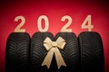 Car tires, new tyres, winter wheels isolated on christmas red background with text happy new year 2024 Royalty Free Stock Photo