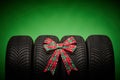 Car tires, new tyres, winter wheels isolated on green background with bow ribbon present Royalty Free Stock Photo