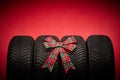 Car tires, new tyres, winter wheels isolated on red christmas background with bow ribbon present Royalty Free Stock Photo