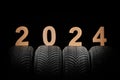 Car tires, winter wheels and text new year 2024 isolated on black background Royalty Free Stock Photo