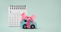 Car toy with bow and calendar on green background Royalty Free Stock Photo