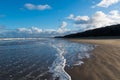 Car tracks on beach with dramatic light and sky reflected in water Royalty Free Stock Photo