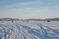 Car tracks lead to Fishermen who catch fish on the Great Frozen Lake, against the backdrop of the mountains, in winter. Royalty Free Stock Photo