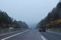 Car traffic on higway with fog and autumn forest on sides