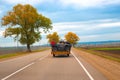 A car with a trailer loaded with ATVs is driving along a country road. Travel and tourism, recreation and entertainment