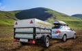 Car with a trailer travels through a field