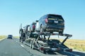 Car transporter carries California highway patrol cruisers along the highway, back view of the trailer