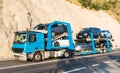 Car Transporter carrying. injured cars transported on the car platform on a mountain road. truck carrying cars