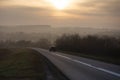 Car traveling on the asphalt road in a rural autumn landscape at sunset Royalty Free Stock Photo