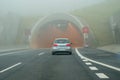 Car before tunnel on foggy road