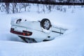 Car turned over after accident in mountains in deep snow after snowfall, back view, car rides of icy slippery mountain road