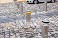 Car is waiting near electric gray hydraulic bollard with a yellow reflective stripe barrier regulating traffic.