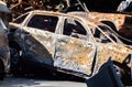 The car was completely destroyed by fire. Abandoned, burnt and rusty car by the road. Cars were on fire in the parking lot. War of Royalty Free Stock Photo