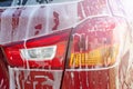 Car wash background. Close up of rear taillight on black modern luxury car covered with washing foam-soap Royalty Free Stock Photo