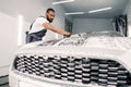 Car wash and clean with soap and sponge. Young concentrated African American man worker, wearing gray overalls and black Royalty Free Stock Photo