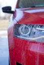 Car wash close-up. Washing a modern car with high-pressure water and soap, cleaning the headlights Royalty Free Stock Photo