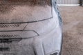 Car wash with Karcher. A man applies shampoo to a black car