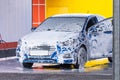 Car wash with open door covered in white foam Royalty Free Stock Photo