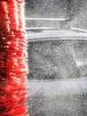 Car wash with red brush roller that sprinkles water droplets