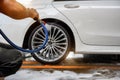 Car wash service, cleaning tires and wheels with cleaning soap foam covered and high-pressure water jet Royalty Free Stock Photo