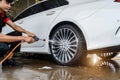 Car wash service, cleaning tires and wheels with cleaning soap foam covered and high-pressure water jet Royalty Free Stock Photo