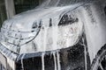 Car wash with soap. Black car covered by foam. Royalty Free Stock Photo